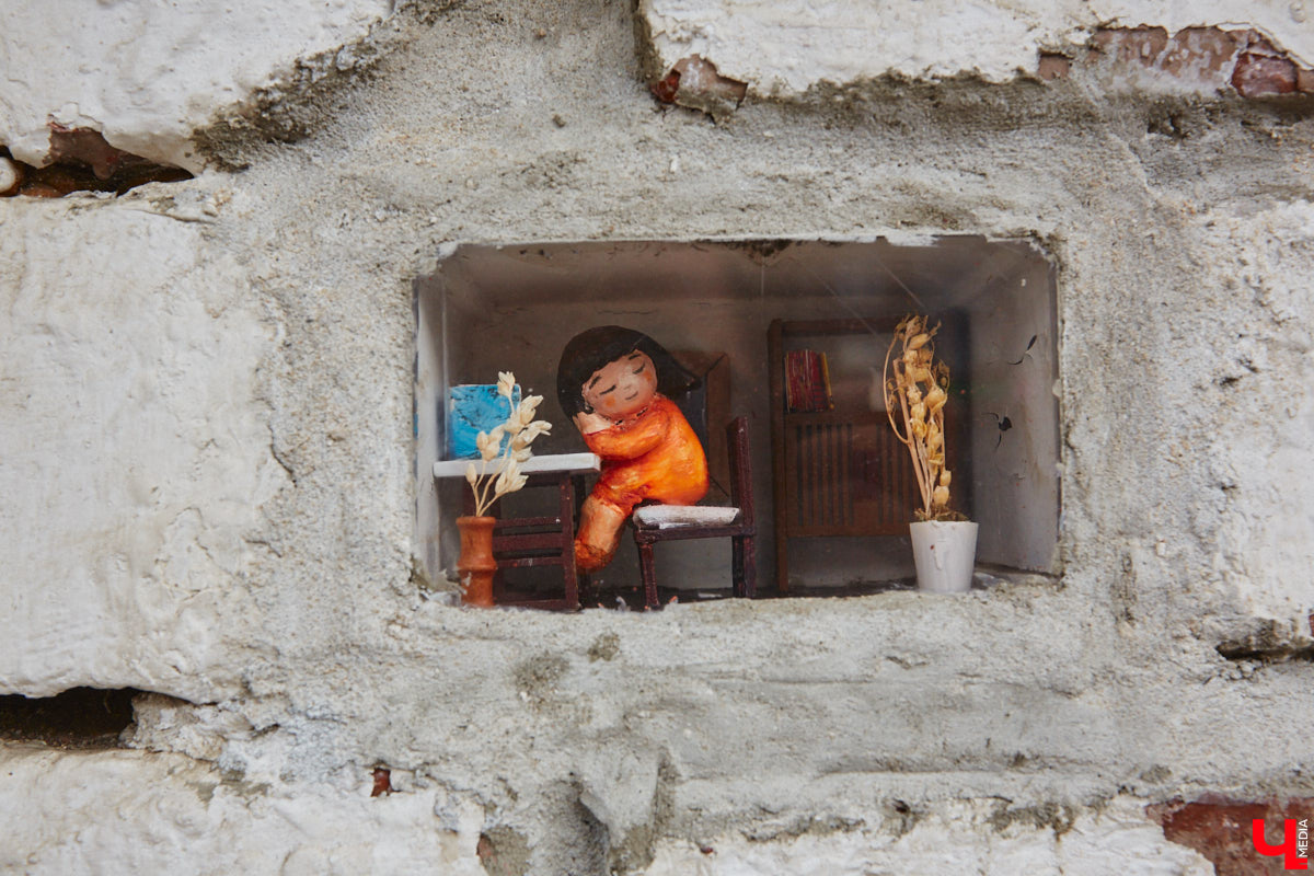 Уличные художники Регина Яфасова и Федор Карпов создали очередную мини-инсталляцию в кирпичной кладке, уже двадцатую по счету. За стеклом стилизованная комната из 90-х годов, на стене которой висит плакат с надписью «Миру — мир, мне — кефир».