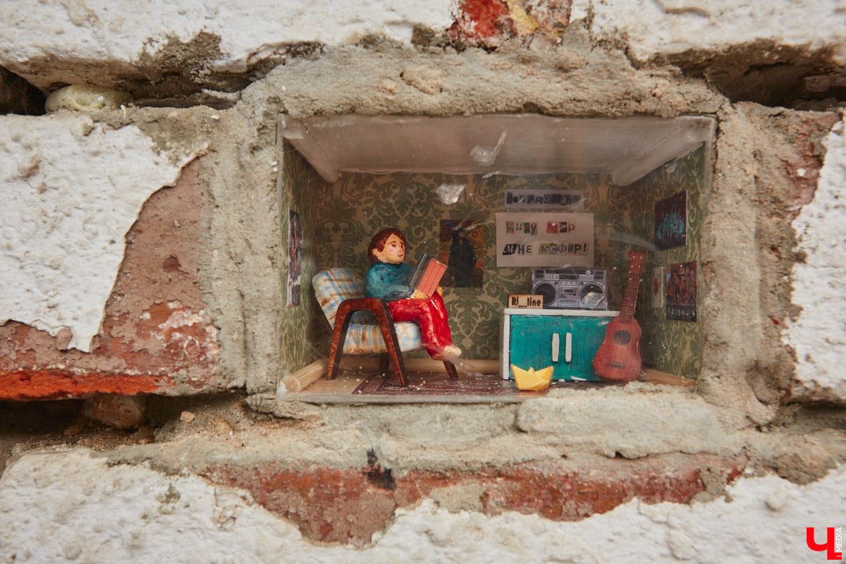Уличные художники Регина Яфасова и Федор Карпов создали очередную мини-инсталляцию в кирпичной кладке, уже двадцатую по счету. За стеклом стилизованная комната из 90-х годов, на стене которой висит плакат с надписью «Миру — мир, мне — кефир».